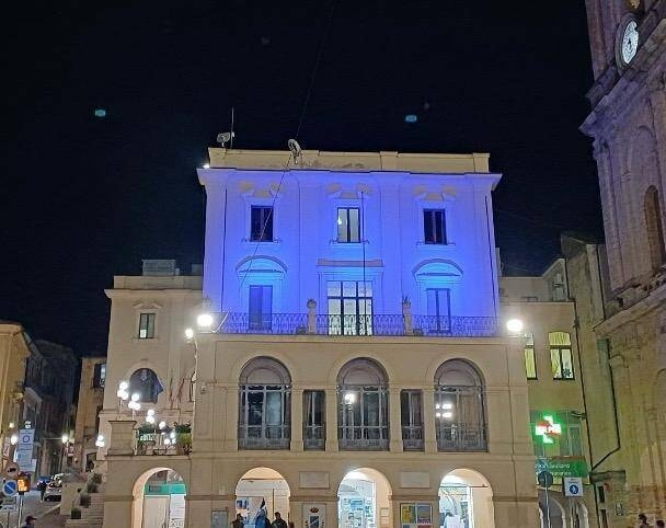 Foto della facciata principale del Municipio illuminata di blu